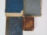 several old books are stacked on top of each other on a white surface