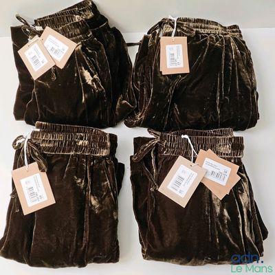 four pairs of brown velvet pants with tags on them sitting on a table