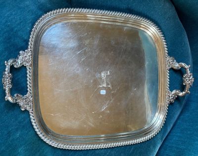 un plateau en argent muni d'une poignée, posé sur un tissu bleu