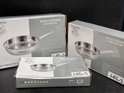 trois casseroles et poêles en acier inoxydable, emballées dans leur boîte, posées sur une table