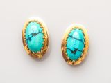 une paire de boucles d'oreilles en turquoise posées sur un fond blanc