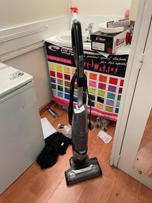 un aspirateur posé par terre à côté d'une machine à laver