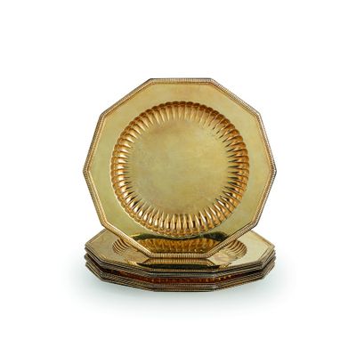 une assiette en or posée sur un support en bois, sur une surface blanche