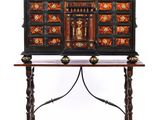 a black and gold painted chest on a stand with a wooden top