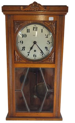 une image représentant une horloge en bois dont la face avant est recouverte d'une vitre