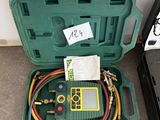 une mallette verte contenant deux tuyaux et un compteur