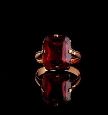 a close up of a ring with a red stone on a black surface
