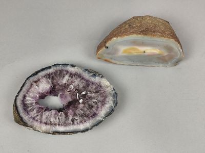 deux morceaux d'améthorate posés sur une surface blanche, à côté d'un morceau de roche