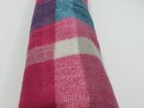 pink, blue, and white striped blanket folded on a white surface