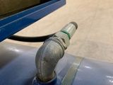 a pipe attached to a blue tank in a warehouse
