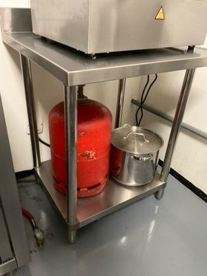 a red gas can sitting on a stainless steel shelf