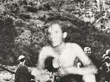 Photographie en noir et blanc d'un groupe d'hommes roulant à moto sur un chemin de terre
