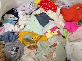 a large pile of baby clothes in a bin on the floor