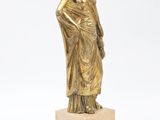a gold statue of a woman standing on top of a marble block
