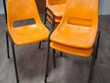 trois chaises en plastique orange posées sur un parquet en bois massif