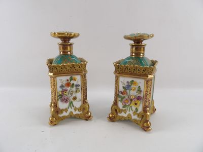 pair of gold and green vases with flowers on them on a white surface