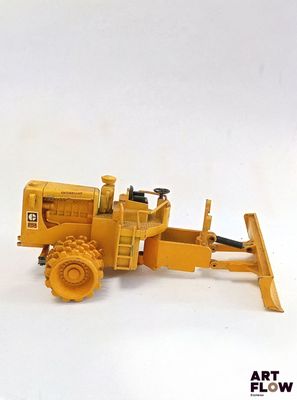 un petit bulldozer jaune posé sur une surface blanche