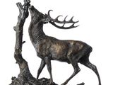 sculpture en bronze représentant un cerf debout près d'un arbre, sur fond blanc