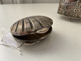 a silver shell on a table next to a silver container