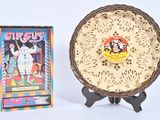 une assiette ornée d'une illustration, à côté d'une boîte de cartes de cirque