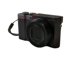 a black digital camera with a cord attached to it
