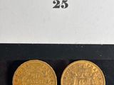 a pair of two gold coins sitting on top of a black surface