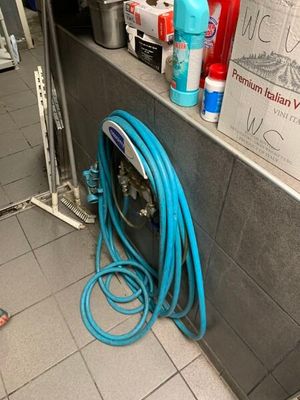 un tuyau bleu posé par terre près d'un mur
