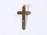 a small cross on a white surface with a gold chain