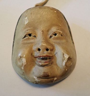 un masque en céramique représentant un visage, posé sur une table