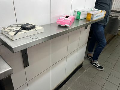 une personne debout devant un comptoir, tenant une boîte de nourriture