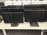 rows of computer monitors sitting on top of a white table in a room