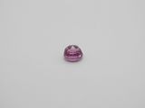 a pink sapphire stone on a white surface