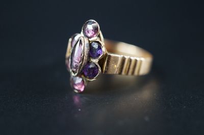 un gros plan d'une bague en or sertie de pierres violettes sur un fond noir