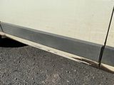 une camionnette blanche avec une bande noire, garée sur le bord de la route