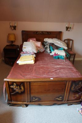 un lit avec une tête de lit en bois et une couverture rose posée dessus