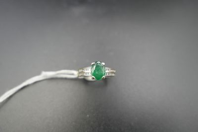 a close up of a ring with a green stone on a black surface