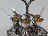 un plateau en argent sur lequel sont disposées quatre tasses et cuillères en argent