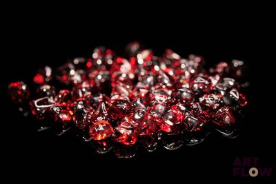 quelques perles de verre rouges sur une surface noire avec un fond noir