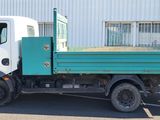 un camion vert et blanc garé devant un immeuble