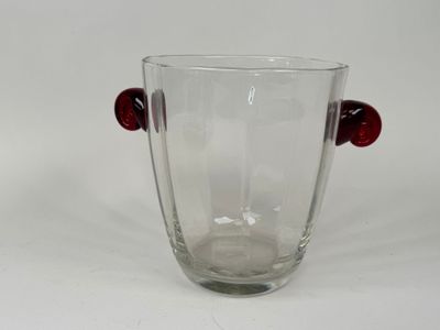 a glass vase with red handles on a white surface
