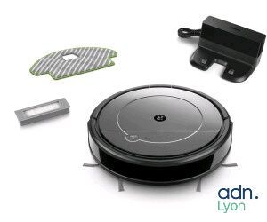 une photo représentant un aspirateur robot et ses accessoires posés sur une surface blanche