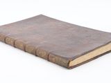 an old book sitting on top of a table on a white surface