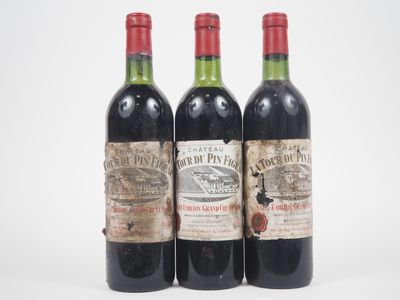 trois bouteilles de vin rouge posées l'une à côté de l'autre sur une surface blanche