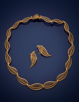 a gold necklace and earrings with leaves on a blue background