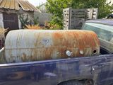 a rusted truck with a tank in the back of it