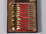 several spoons are in a wooden box with red cloth
