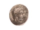 une vieille pièce de monnaie avec un visage d'homme sur une surface blanche