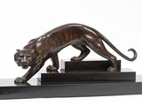 statue en bronze représentant un tigre, posée sur un socle noir, sur fond blanc