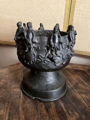 statue représentant un groupe de personnes dans un bol posé sur une table en bois