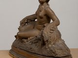 bronze statue of a woman sitting on a rock with a dog